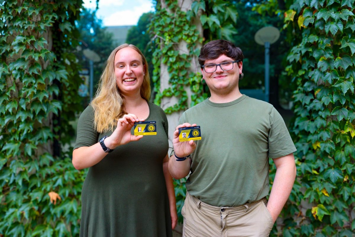 (From left to right) Senior James Renton stands next to senior Meg Booker holding their student IDs from their freshman year. 
