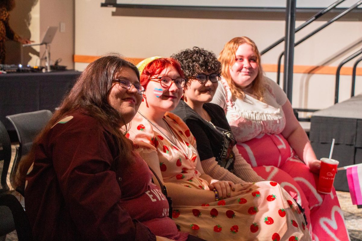 Students smiling as they watch performances at LGBTQA+ Student Initiatives annual drag show. 