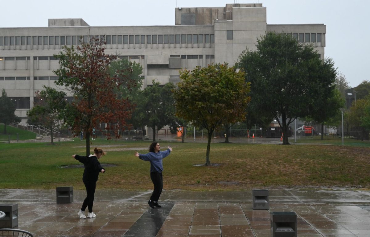 Two students dance in the rain, embracing the downpour in front of Griffin Lawn. 