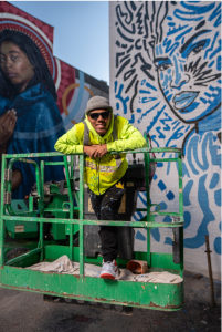 Javarri Lewis posing in front of his mural he painted with Kingsley Nebechi for BLINK 2022. This mural is located at the Pleasant Street entrance at Findlay Market. Provided by Javarri Lewis.
