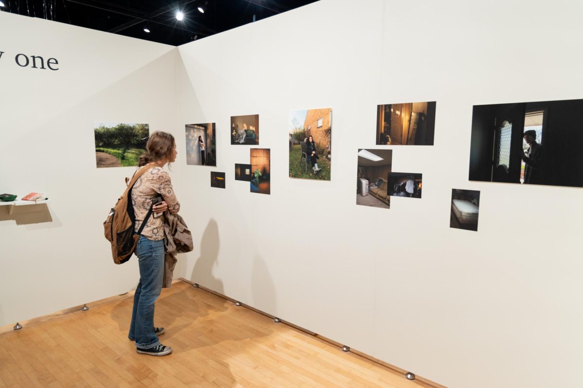 Audience views photographic exhibit by Elly Wiggins. Titled “one thirty one,” this exhibit looks to explore family dynamics and taking over as a caretaker for her mother.