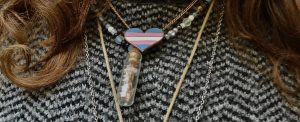 Natelie Smith wears a transgender flag heart around her neck, layered with some of her other favorite necklaces. 